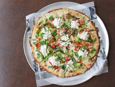 Vegetable Pizza with broccoli, peppers and ricotta cheese on round plate